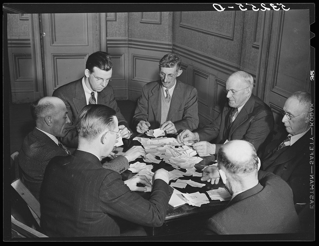 Townspeople seated around a table sorting and organizing cards and ballots at a town meeting in Woodstock, Vermont, 1940.